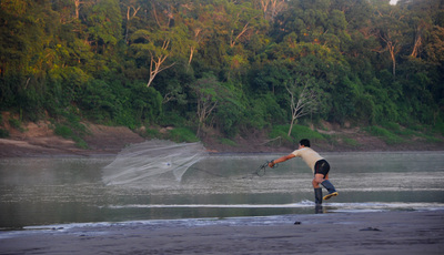 Local man throwing fishing net on Tambopata River